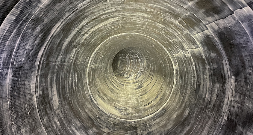 A view of the inside of a water pipeline lined with silver-colored carbon fiber lining.